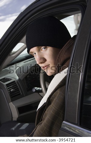 Caucasian male teenager sitting in car looking back at viewer.