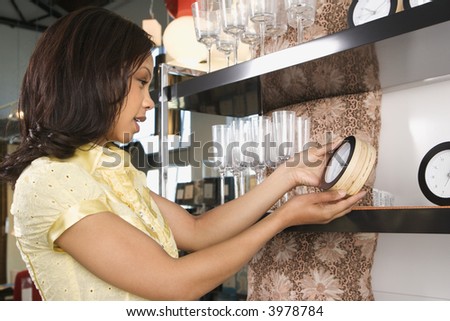 African-American female shopping for clocks in retail shopping setting.