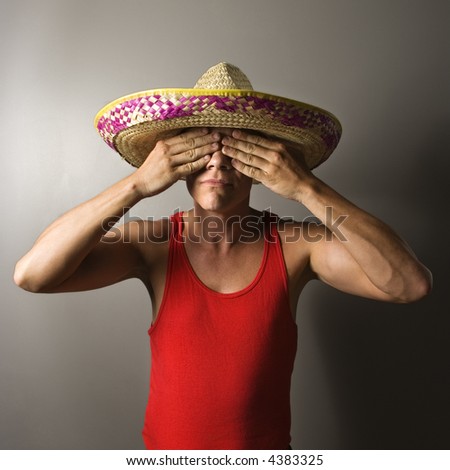 Portrait of a mid-adult Caucasian male wearing sombrero with hands over eyes.