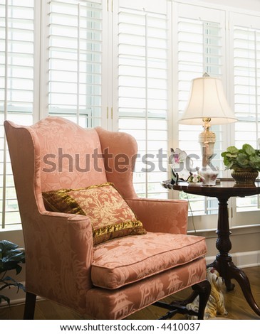 Still life of chair in living room with windows in background.