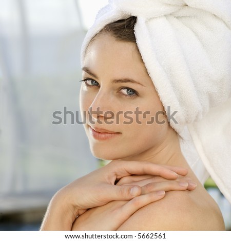 Caucasian mid-adult woman wearing towel around head with hands on shoulder looking at viewer.