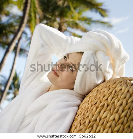 Caucasian mid-adult woman wearing robe and towel on head with hand to head.