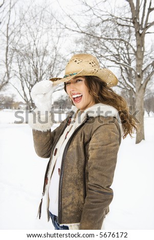 Caucasian young adult female winking and tilting straw cowboy hat at viewer.