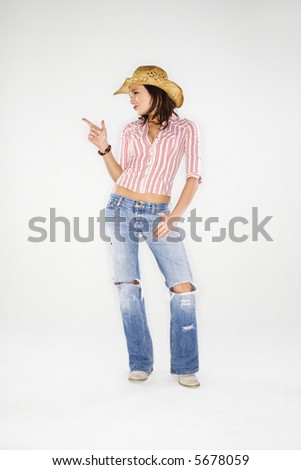 Young adult Caucasian woman wearing cowboy hat pointing finger like a gun.