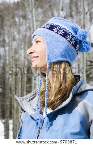 Side view head and shoulder of attractive smiling mid adult Caucasian blond woman wearing blue ski clothing.