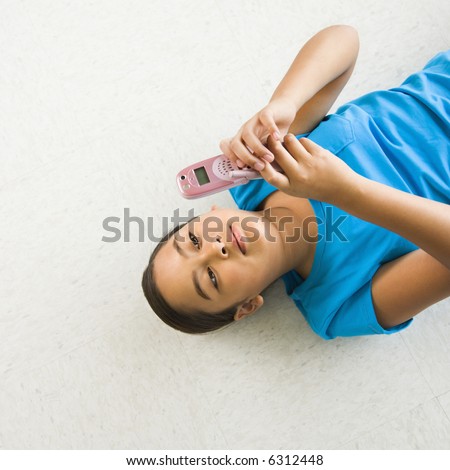 stock photo Asian preteen girl lying on back on floor text messaging on 
