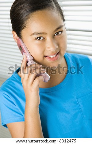 stock photo Asian preteen girl talking on cell phone and looking at viewer 