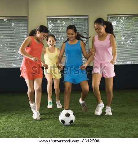 stock photo Four multiethnic girls playing soccer and laughing in indoor