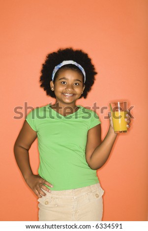 African American girl with hand on hip holding glass of orange juice.