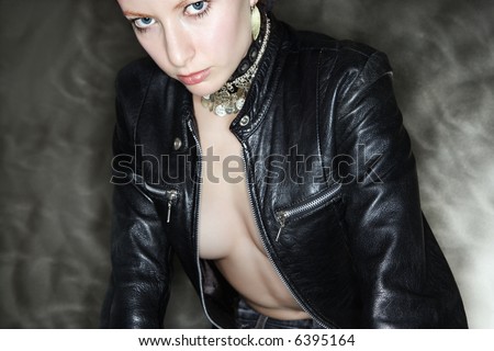 Partially nude Caucasian woman in leather jacket looking at viewer.