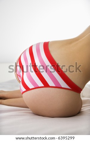 stock photo Close up back view of woman in striped panties kneeling on bed