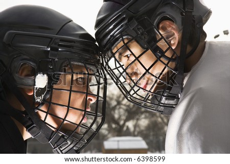 Two ice hockey players in uniform facing off trying to intimidate eachother.