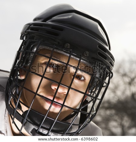 Boy in ice hockey uniform making eye contact.