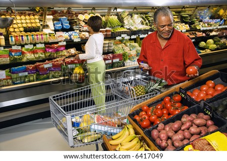Middle aged African American man and woman in grocery store shopping for produce.