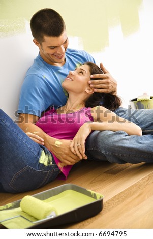 Couple sitting on floor embracing taking break from interior painting.