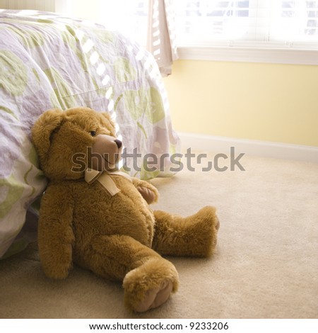 Plush brown teddy bear on bedroom floor.