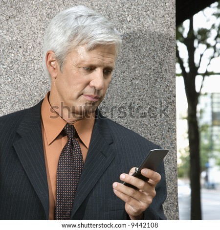 Caucasian middle aged businessman looking down at cell phone.