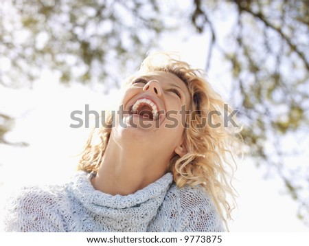 Pretty young blond woman in Maui, Hawaii leaning head back and laughing.