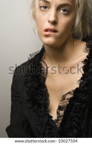 Caucasian woman biting lip and looking at viewer.