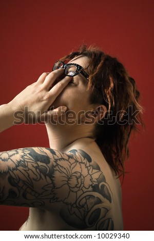 stock photo : Adult woman with tattoos rubbing her eyes.