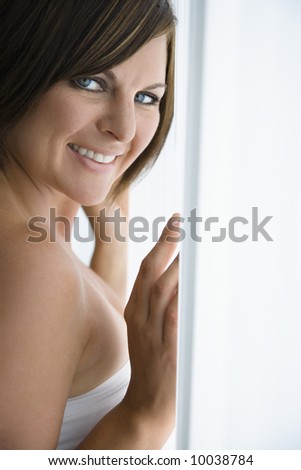 Caucasian mid adult brunette woman near window smiling