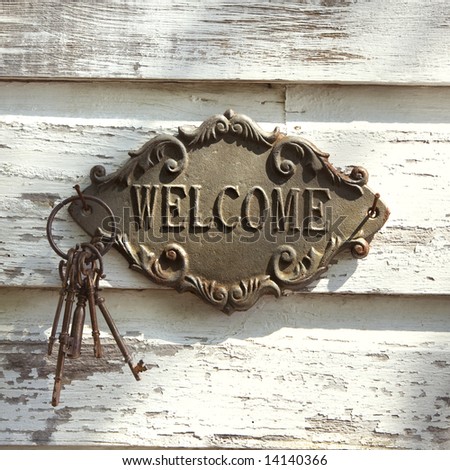 Welcome sign and metal keys on old white peeling building.