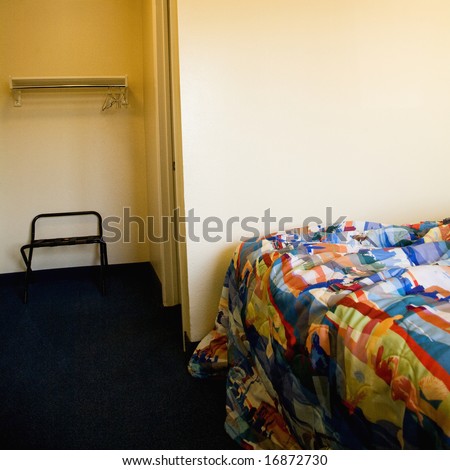 Interior shot of motel room with unmade bed and closet.