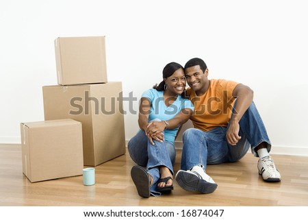 African American male and female couple sitting on floor next to moving boxes.