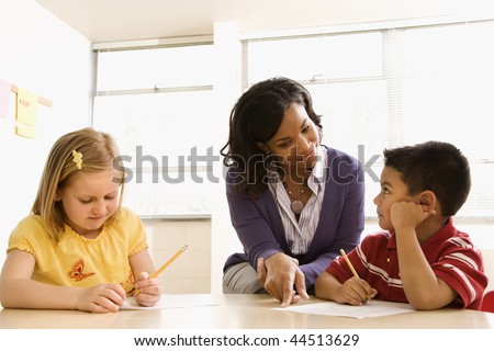 Teacher helping students with schoolwork in school classroom. Horizontally framed shot.