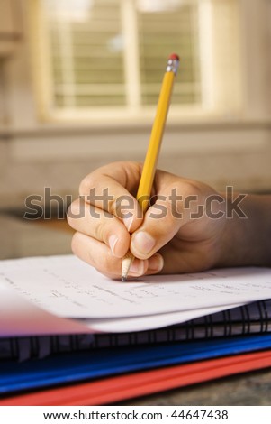 Child\'s hand holding pencil doing homework. Vertically framed shot.