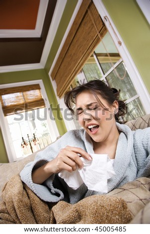 Young ill woman in a bathrobe about to sneeze. Vertical shot.