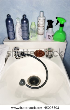 Hair products and beauty supplies on a washing sink at a salon.  Vertical shot.