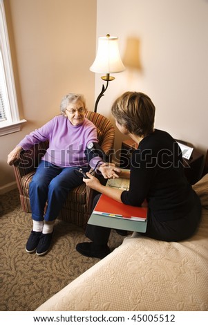 Nurse checking an elderly woman\'s blood pressure in assisted living home. Vertical shot.