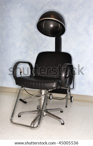 Empty styling chair and hair dryer at a salon.  Vertical shot.