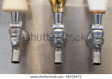 Three beer tap spouts with condensation showing on the openings. Horizontal shot.