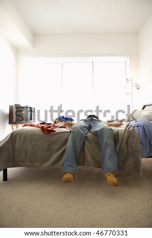 Man lying on bed. Only his lower body is viewable. Vertical shot.