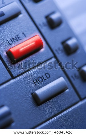 Close up of a multi-line office telephone with lit line one button. Vertical shot.