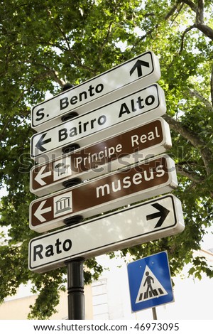 Low angle view of pedestrian crossing sign and directional signs in Lisbon, Portugal. Vertical shot.