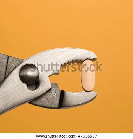 Pill being gripped with pliers. Square format. Isolated on orange.