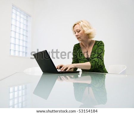 Caucasian middle aged businesswoman in office working on laptop computer.
