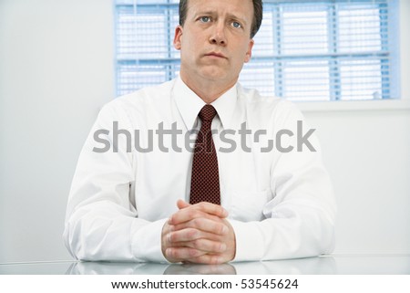 Caucasian middle aged businessman sitting at desk in meditation.