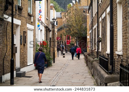 LONDON, UK - SEPTEMBER 7TH, 2014: people walking (and cycling) a narrow street in Greenwich, London