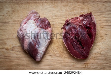 closeup photo of a whole and a cut lamb heart on a chopping board