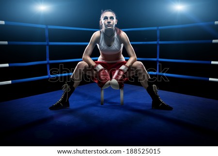 Boxing woman sitting alone in the boxing arena , surrounded by blue lights