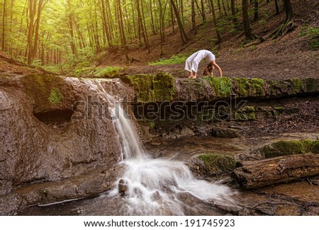 Woman practices yoga in nature, the waterfall. forest; Urdhva phanurasana; Dhanurasana pose.