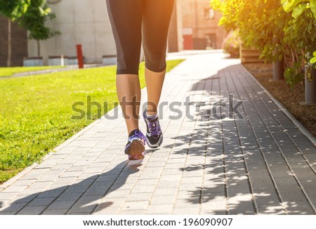 Running woman in black sports outfit (half body photo) on the sidewalk