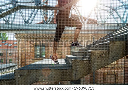 Running woman in black sports outfit, running up the stairs