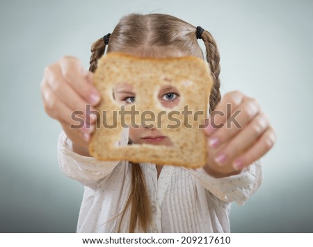 Little girl holding her face in front of a sad slice of bread