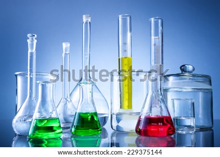 Laboratory equipment, bottles, flasks with color liquid  on blue background