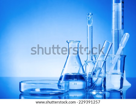 Laboratory equipment, glass flasks, pipettes on blue background